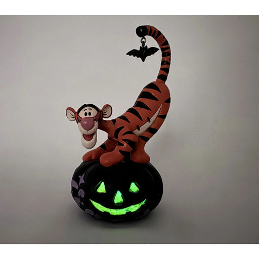 Glowing Halloween-themed figurine of a tiger on a pumpkin with a bat.