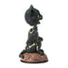 Black cat figurine with green eyes on a decorative base