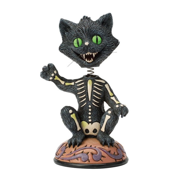 Skeletal black cat figurine with green eyes on a white background
