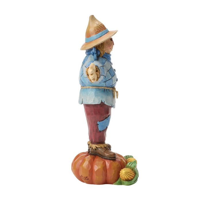 Statue of a character in a blue outfit and straw hat standing on a pumpkin with a white background