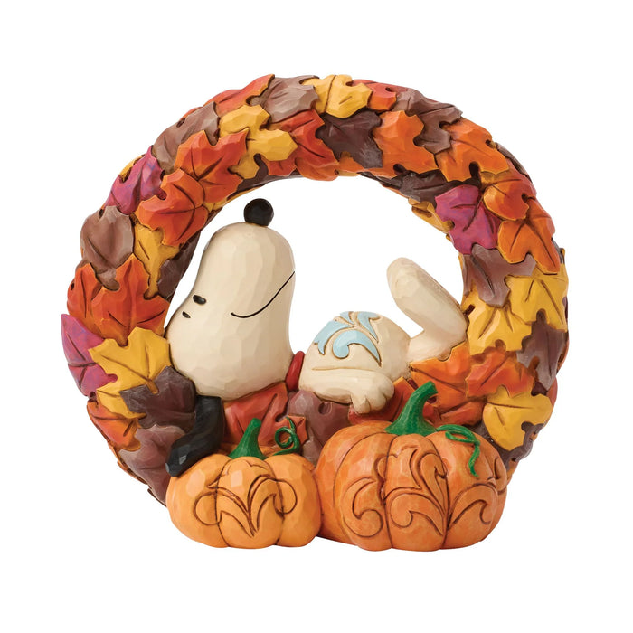 Decorative wreath with autumn leaves, pumpkins, and a small dog figure on a white background