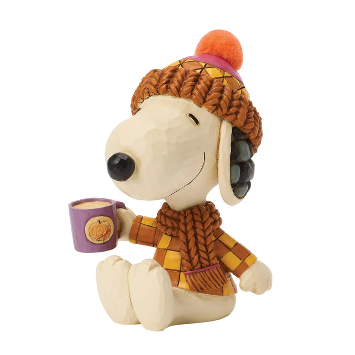 Stuffed dog toy wearing a winter hat and scarf, holding a mug.