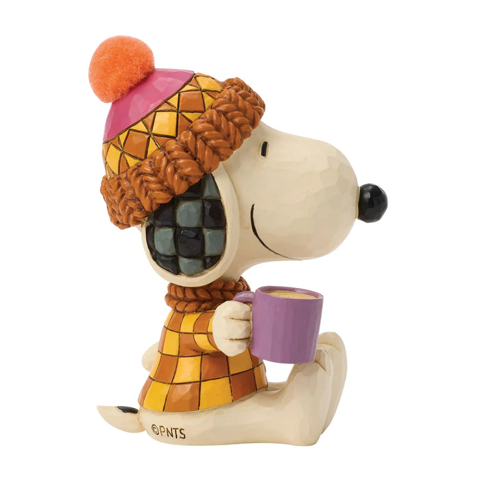 Snoopy figurine wearing a colorful hat and scarf, holding a purple mug on a white background