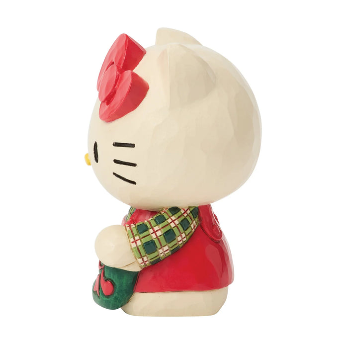 Hello Kitty figurine wearing a Christmas sweater and holding a stocking on a white background
