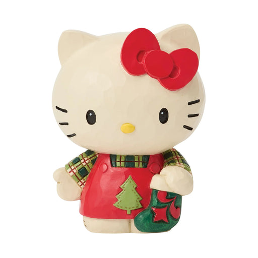 Hello Kitty figurine wearing a Christmas sweater and holding a stocking on a white background