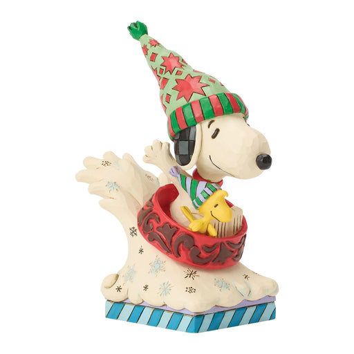 Snoopy and Woodstock figurine with a colorful hats in a red bowl sled on a white background