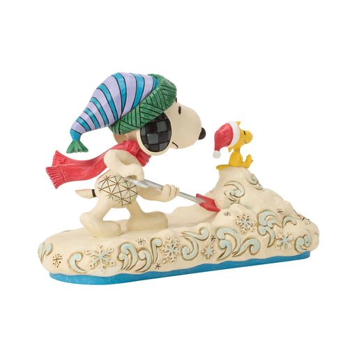 Decorative figurine of Snoopy and Woodstock shoveling snow with festive hats on a white background