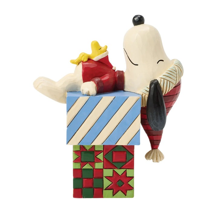 Figurine of a character from Peanuts series hugging a gift box with a white background