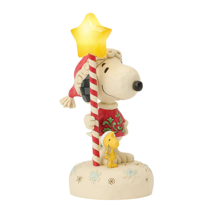 Snoopy figurine with a star on his head and a candy cane, holding Woodstock, on a white background.