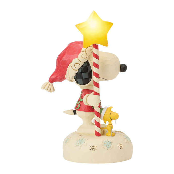 Snoopy figurine holding a star and candy cane on a white background