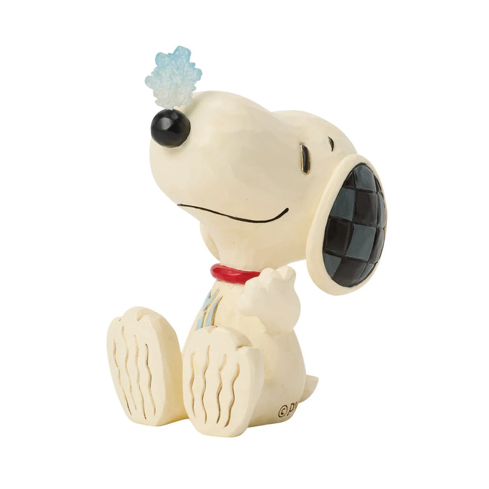 Snoopy figurine with a snowflake on its head against a white background