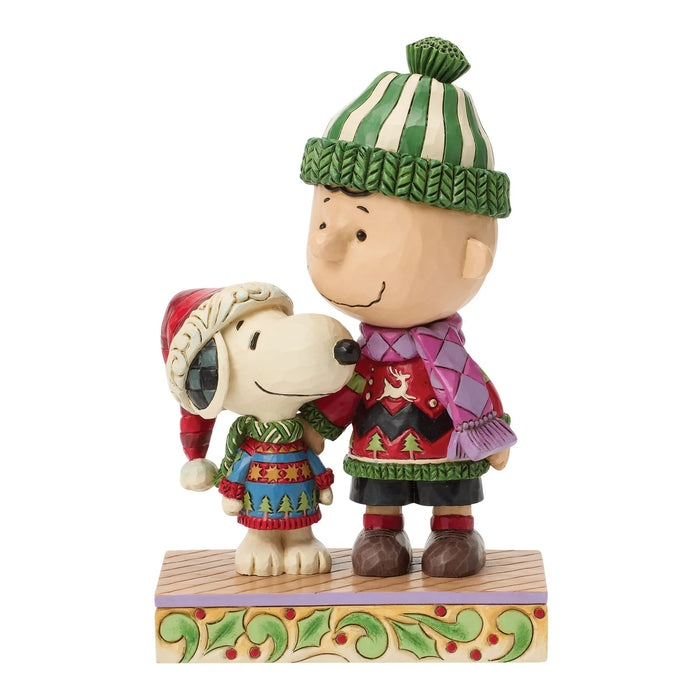 Figurine of a cartoon character and dog wearing Christmas sweaters and hats on a white background.