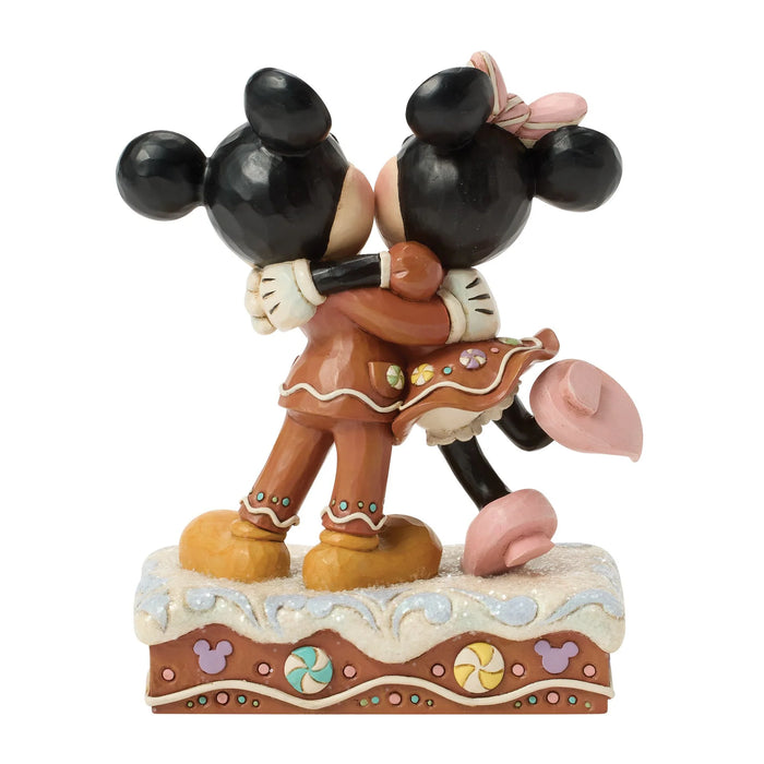 Figurine of a gingerbread man and mouse hugging on a white background