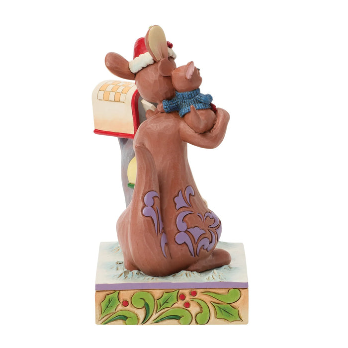 Statue of a bear with a child on its back, wearing a Santa hat, on a decorative base.
