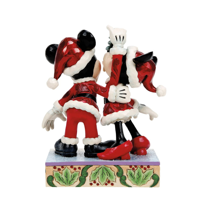 Two cartoon characters in festive outfits on a decorative base with holly design.