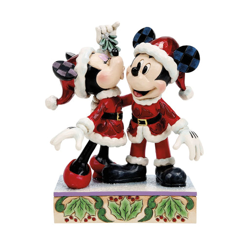 Christmas-themed figurine of a couple in festive outfits on a decorative base.