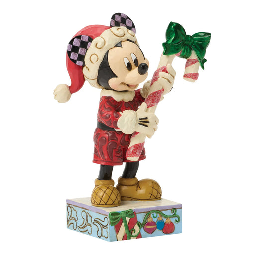 Mickey Mouse figurine in Christmas attire holding a candy cane on a white background