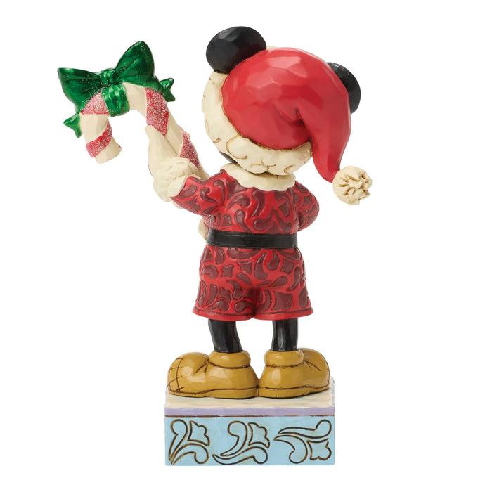 Figurine of a character in a red outfit with a candy cane and green bow on a white background