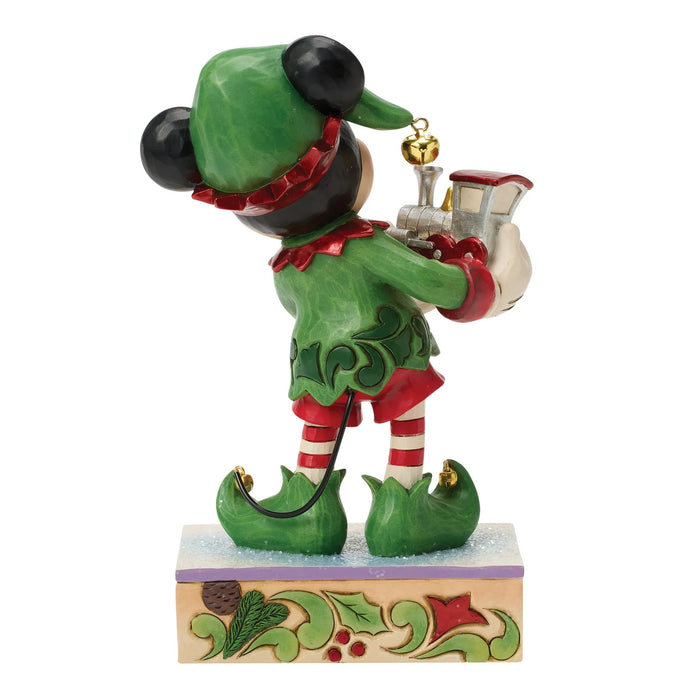 Elf figurine holding a gift on a decorative base with a white background