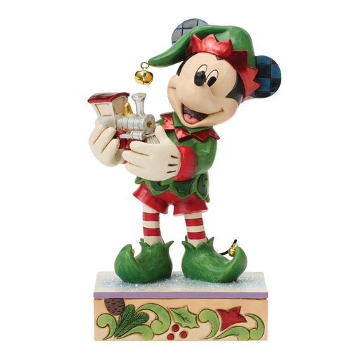 Animated character figurine dressed as an elf holding a small train on a white background