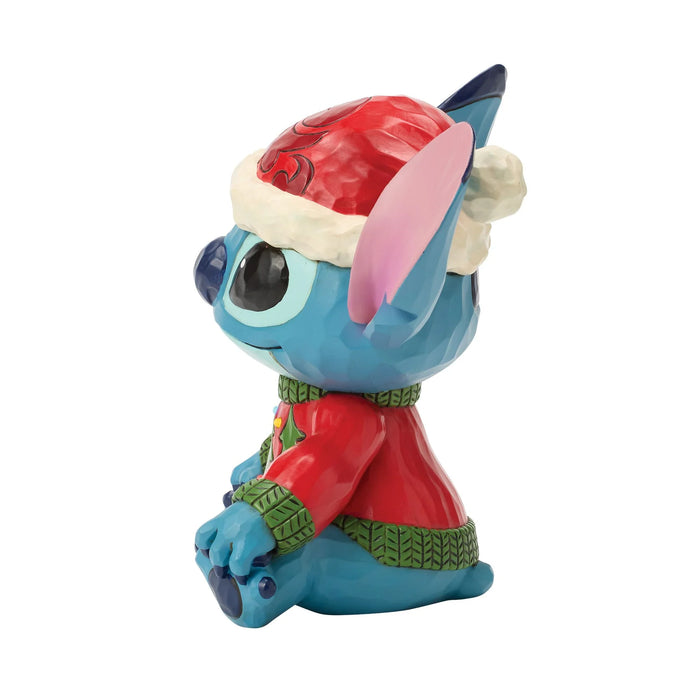 Toy figure of a blue character wearing a Santa hat and red outfit on a white background