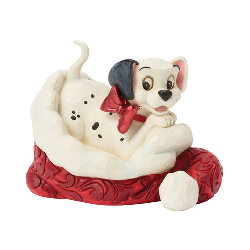 Dog figurine with a red bow tie sitting on a red base against a white background