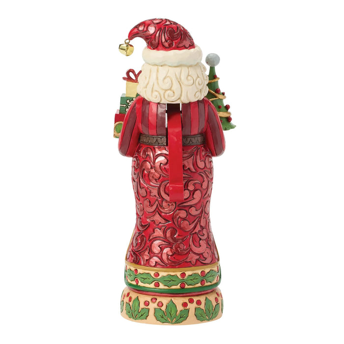 Festive Santa nutcracker figurine holding a Christmas tree and gifts on a white background
