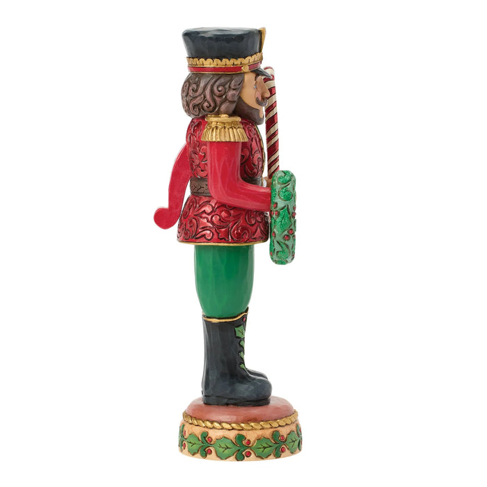 Decorative nutcracker figure with red outfit, green pants, and holding a candy cane on a white background.