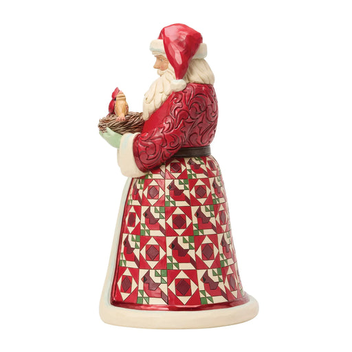 Festive Santa figurine holding a nest of cardinals on a white background