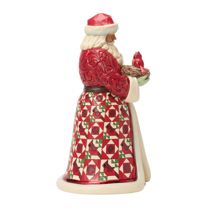 Festive Santa figurine holding a nest of cardinals on a white background