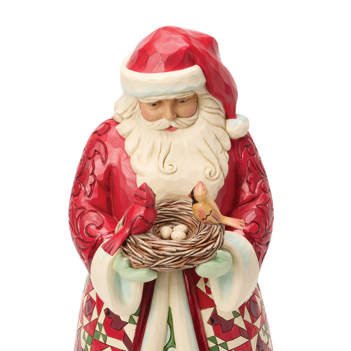 Festive Santa figurine holding a nest of cardinals on a white background