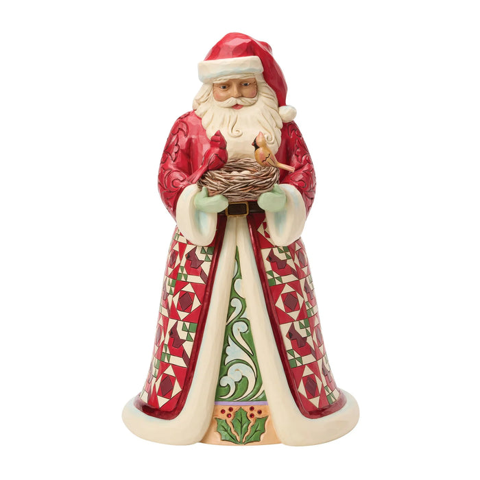 Festive Santa figurine holding a nest of cardinals on a white background