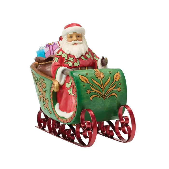 Figurine of Santa in a decorative sleigh with bags of gifts on a white background