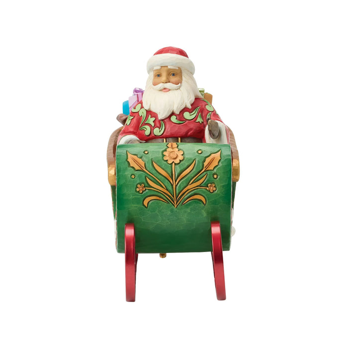 Figurine of Santa in a decorative sleigh with bags of gifts on a white background