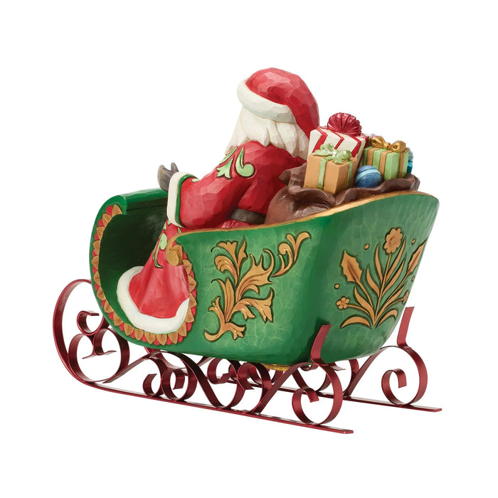 Figurine of Santa in a decorative sleigh with bags of gifts on a white background