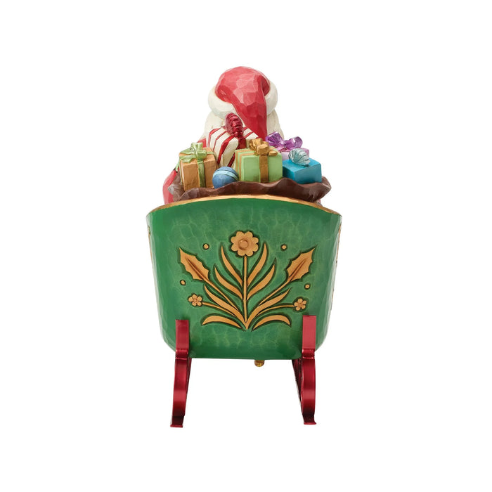 Figurine of Santa in a decorative sleigh with bags of gifts on a white background