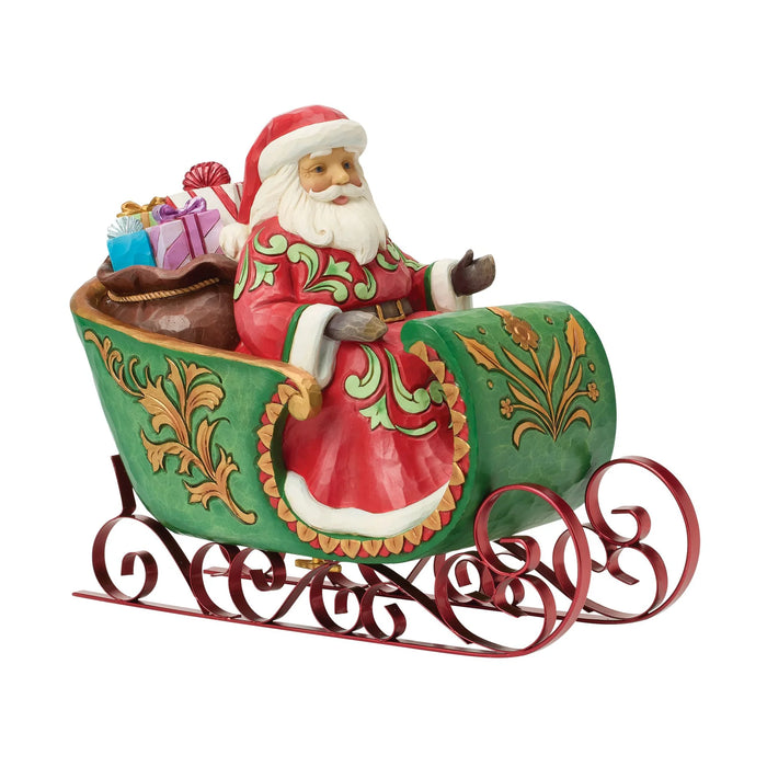 Figurine of Santa in a decorative sleigh with bags of gifts on a white background