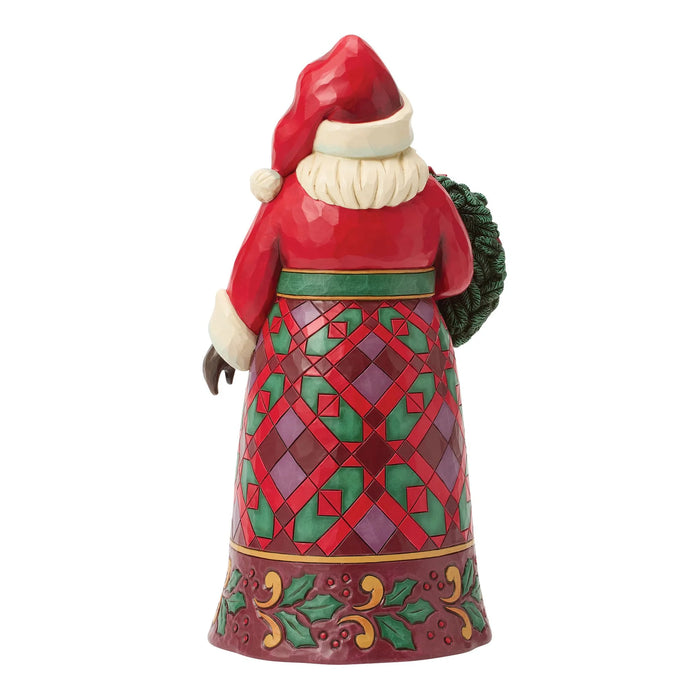 Festive Santa figurine holding a wreath with poinsettias on a white background