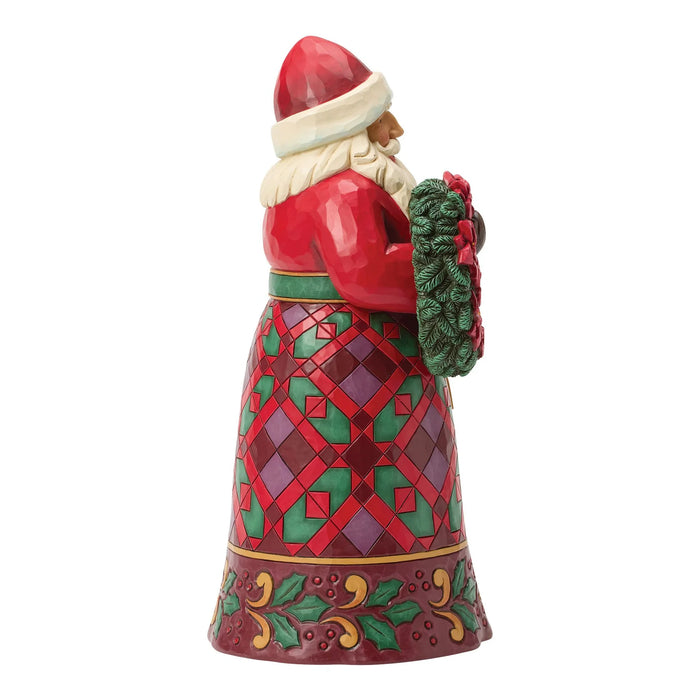 Festive Santa figurine holding a wreath with poinsettias on a white background