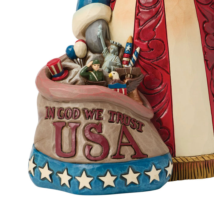 Decorative figurine of a patriotic Santa Claus holding an American flag on a white background