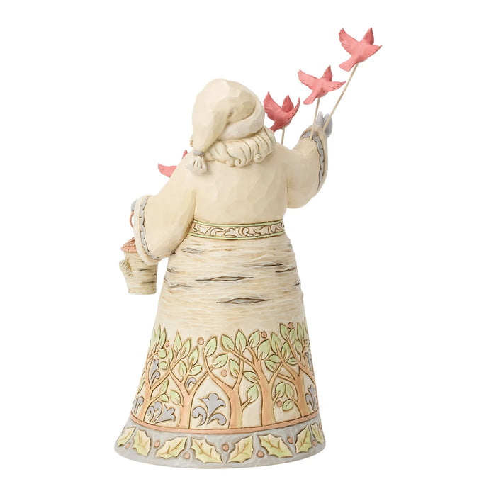 A decorative figurine of a Santa from behind, wearing a cream-colored winter dress and hat, holding pink birds on sticks and a small basket, set against a plain white background.