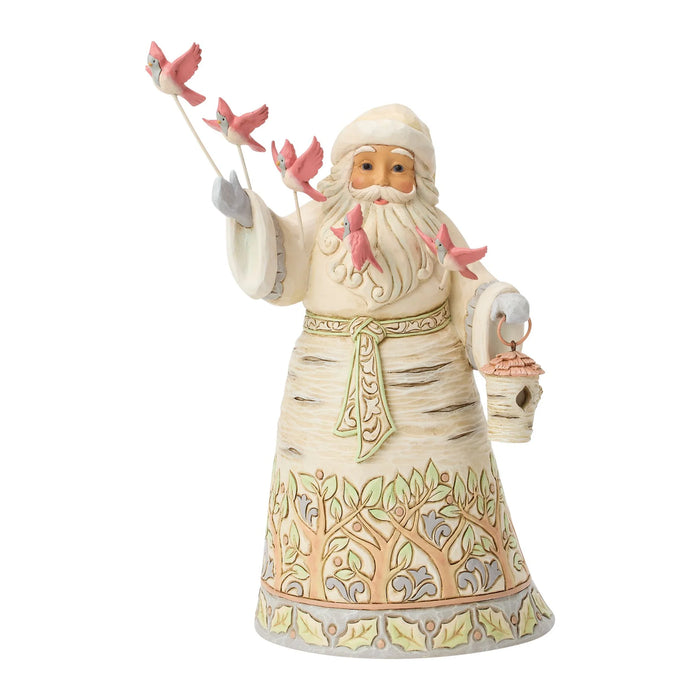 Santa figurine holding a birdhouse with flying cardinals on a white background