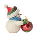 Snowman figurine with a hat and blue scarf holding a green and red ornament that says "Merry Christmas" on a white background