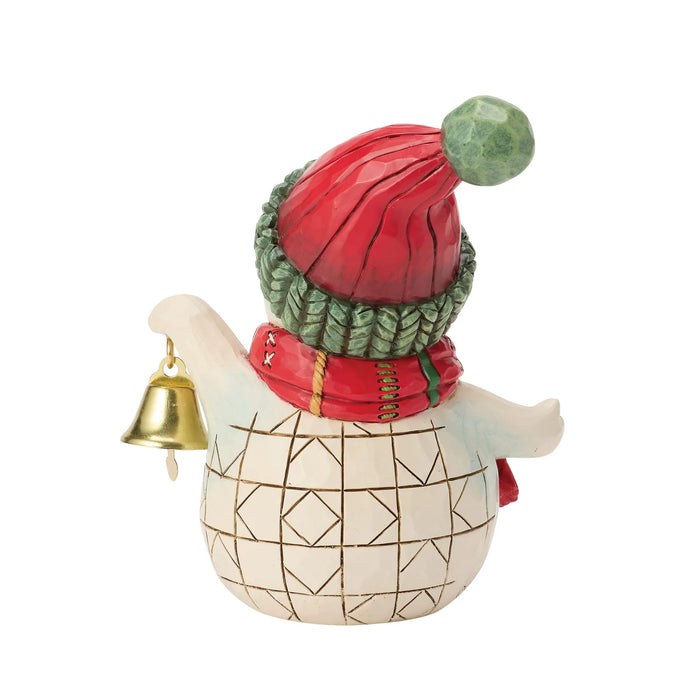 Snowman figurine with red and green hat and scarf holding a bell on a white background