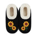 A pair of black slip-on slippers with white sherpa lining and embroidered yellow sunflowers on the front, shown against a plain white background.