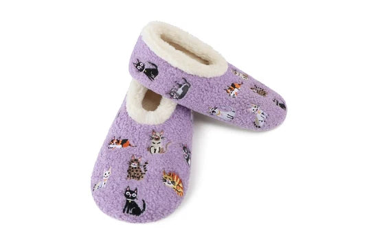 A pair of lavender purple fleece slipper socks featuring a playful print of various cartoon cats in different poses, with a soft cream sherpa lining visible at the opening, set against a plain white background.