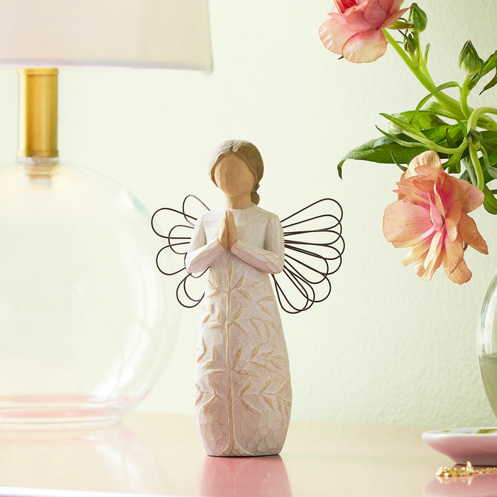 Standing angel in cream dress with wire wings, with hands in prayer position; tree carving on angel's dress