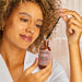Woman holding a bottle of 'kitsch' castor oil with a close-up of the product.