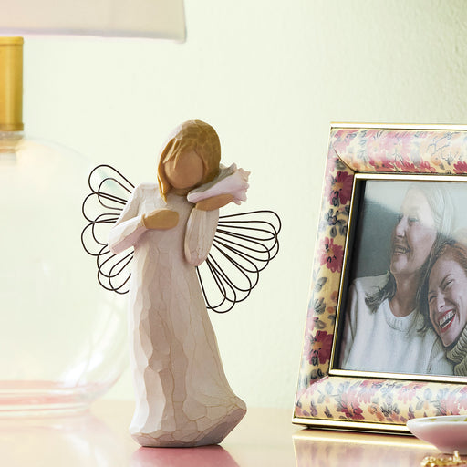 Standing angel in cream dress with wire wings, holding pink conch shell to ear