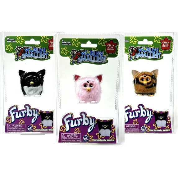 Three packaged Furby toys from Worlds Mallest line, showing the black-and-white cat, pink fluffy cat, and brown cat versions in clear plastic blister packs on a white background.